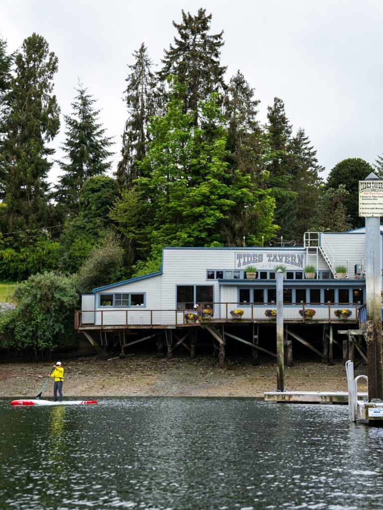 Paddleboarder paddles in front of Tides Tavern
